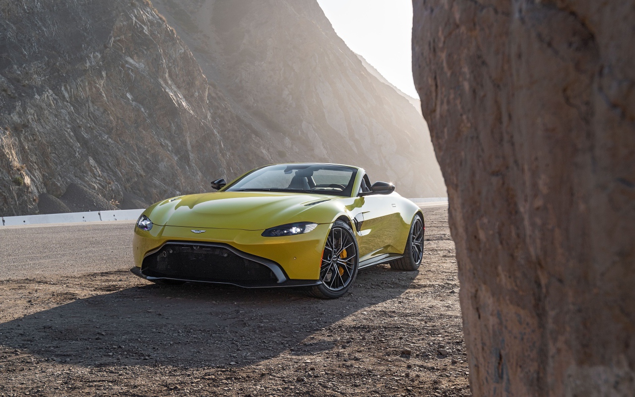 Желтый автомобиль  Aston Martin Vantage Roadster, 2021 года в горах 