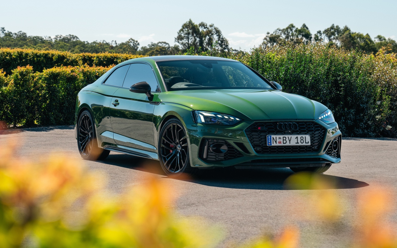 Зеленый автомобиль Audi RS 5 Coupé 2020  года в лучах солнца
