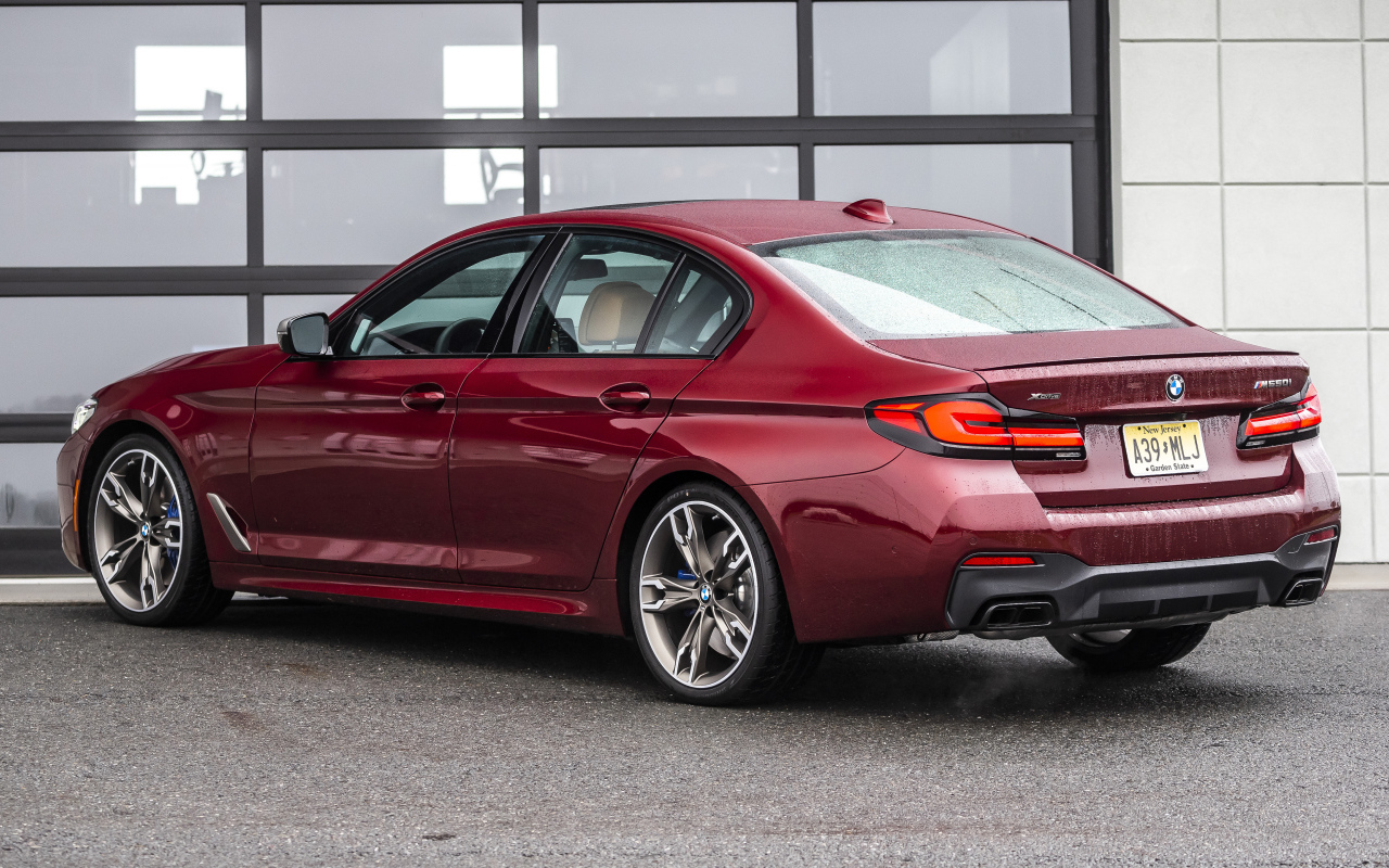 Красный автомобиль BMW M550i XDrive, 2021 года вид сзади
