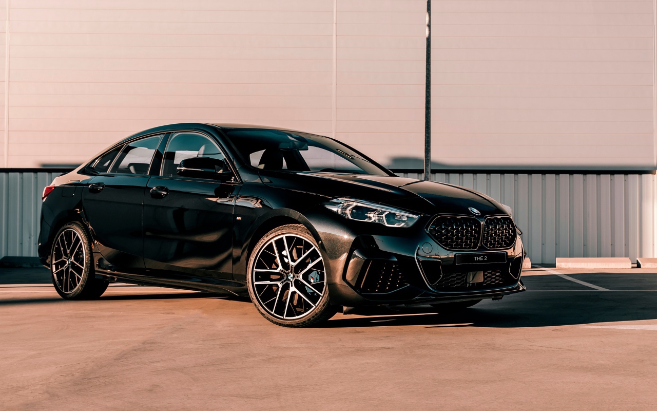 Черный автомобиль BMW M235i XDrive Gran, 2020 года у белого здания 
