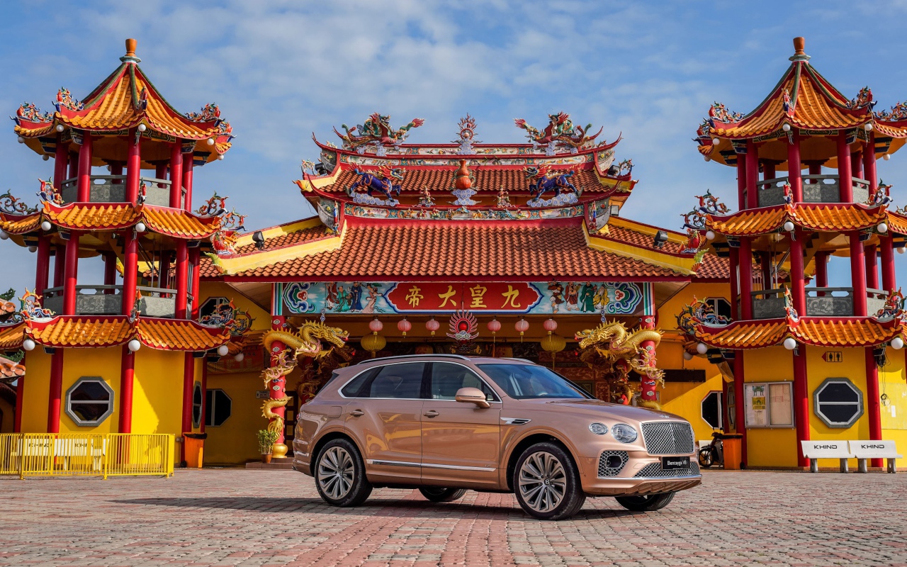 Коричневый автомобиль Bentley Bentayga V8 2020 года на фоне красивого здания