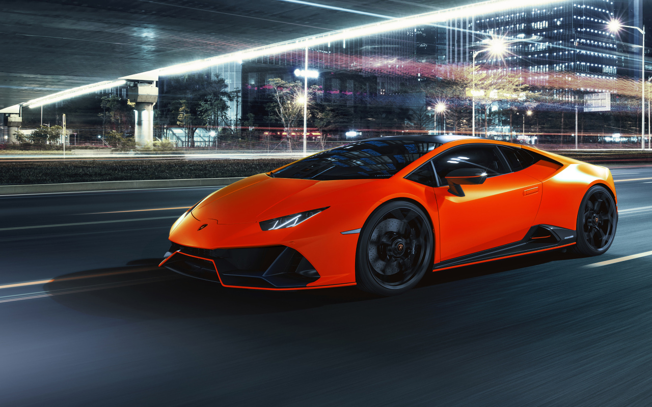 Оранжевый автомобиль Lamborghini Huracán EVO 2021 года на фоне города