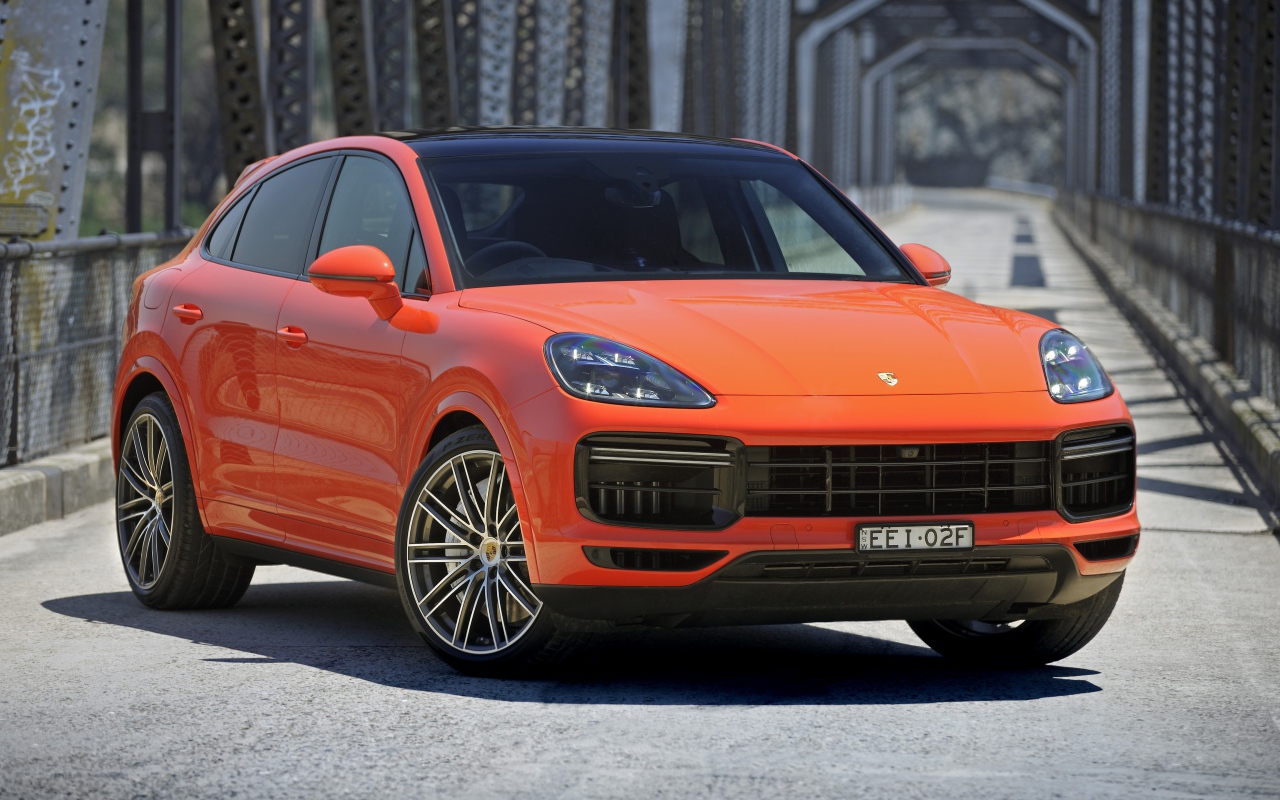 Оранжевый внедорожник Porsche Cayenne Turbo Coupe 2019 года на мосту