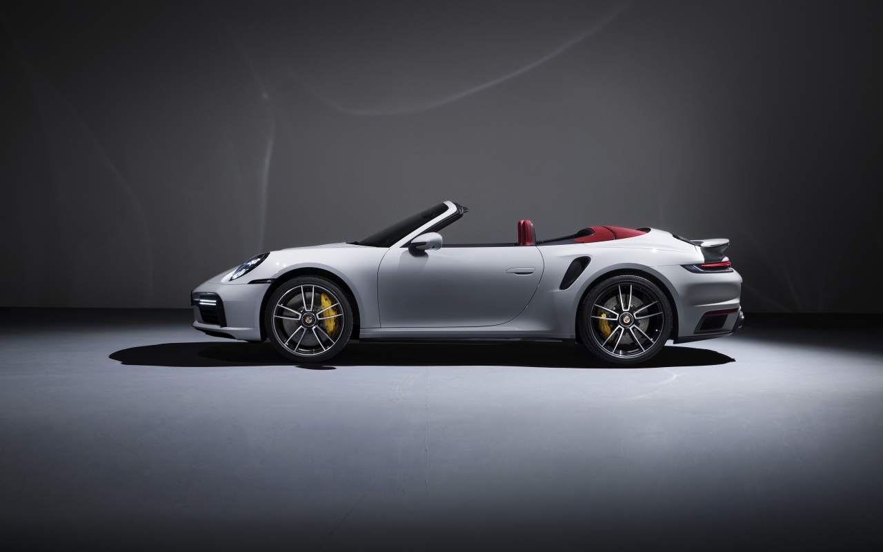 Белый автомобиль Porsche 911 Turbo S Cabriolet 2020 года на сером фоне