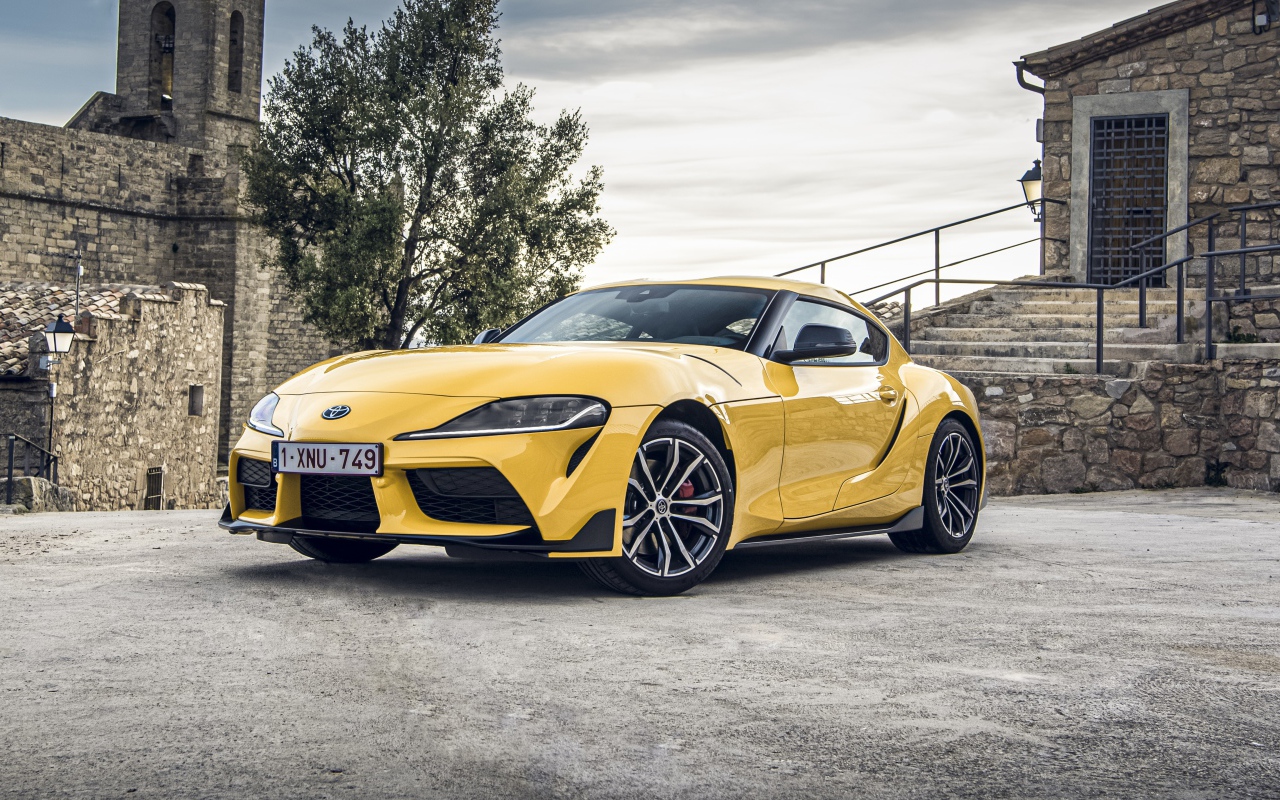 Желтый автомобиль Toyota GR Supra 2, 2020 года у старого здания 