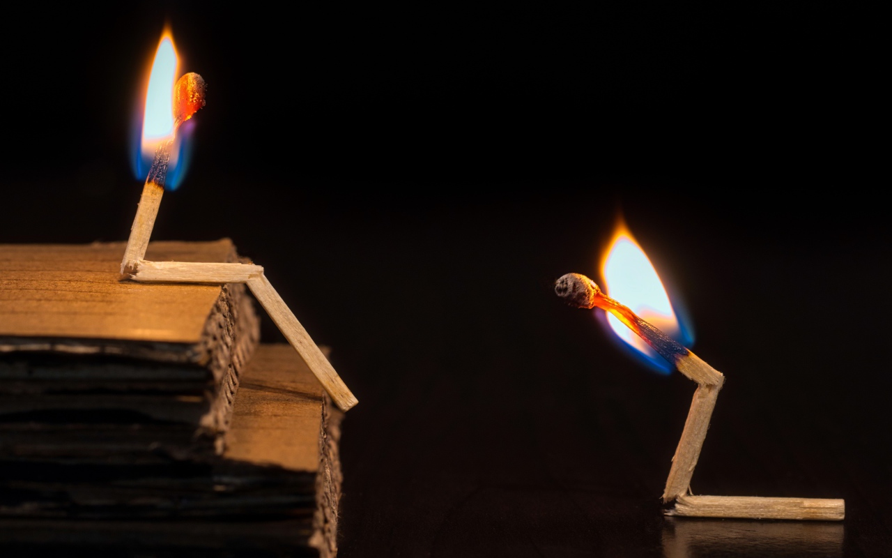Two burning matches on a black background