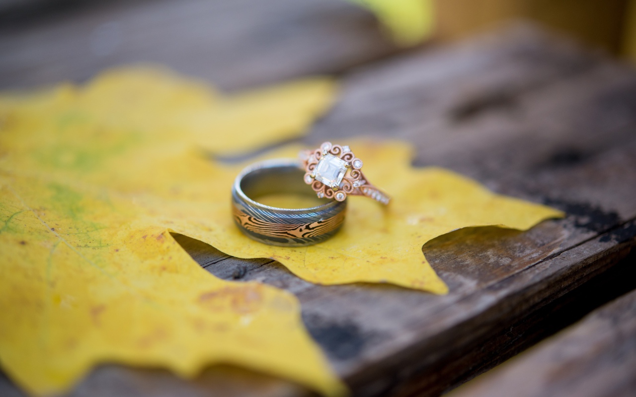 Золотые кольца с желтым листом на столе 