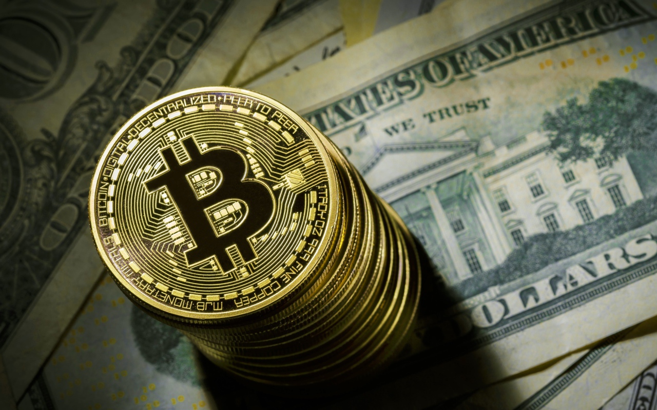 Золотые монеты биткоин лежат на долларах