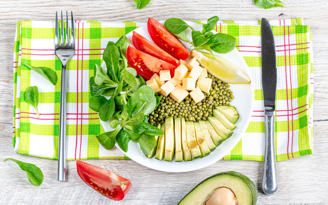 Аппетитные  свежие овощи с сыром и лимоном на тарелке 