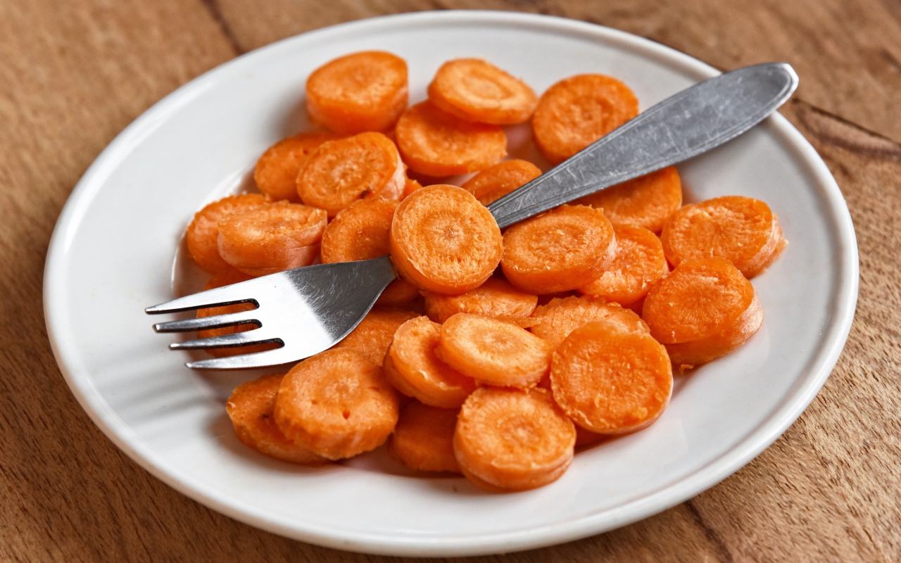 Морковь кружочками на белой тарелке с вилкой