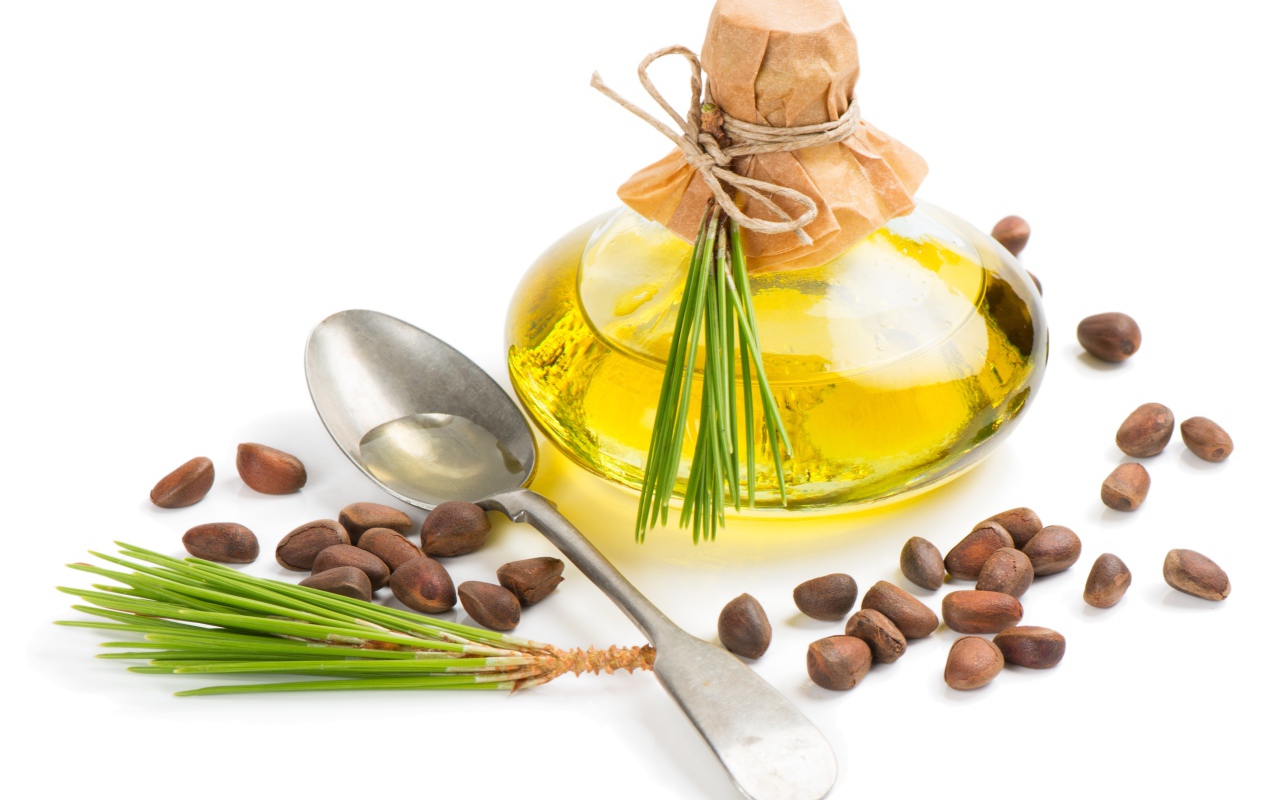 Кедровое масло на белом фоне с орехами и ложкой