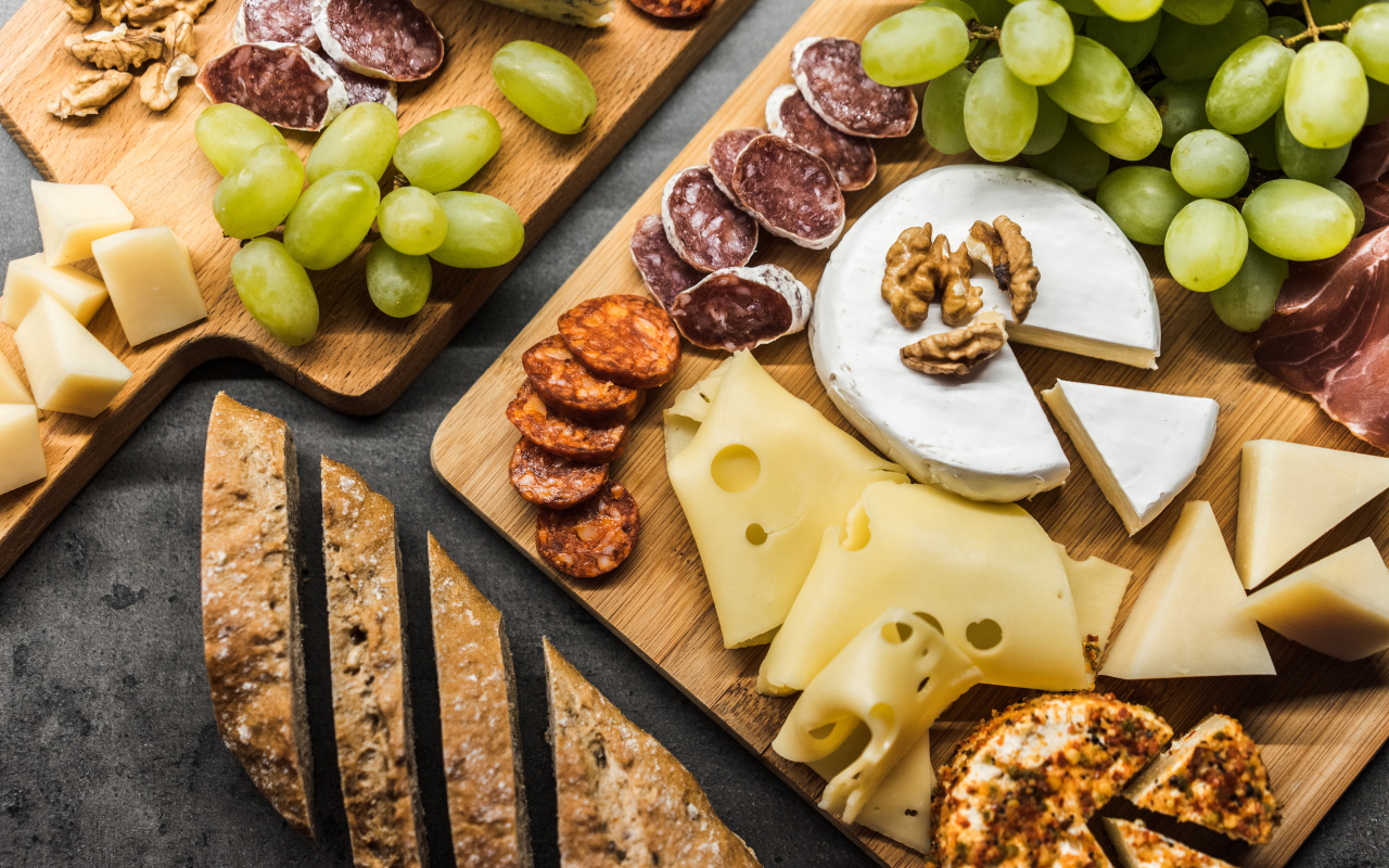 Сыр, колбаса, виноград и батон  на столе 