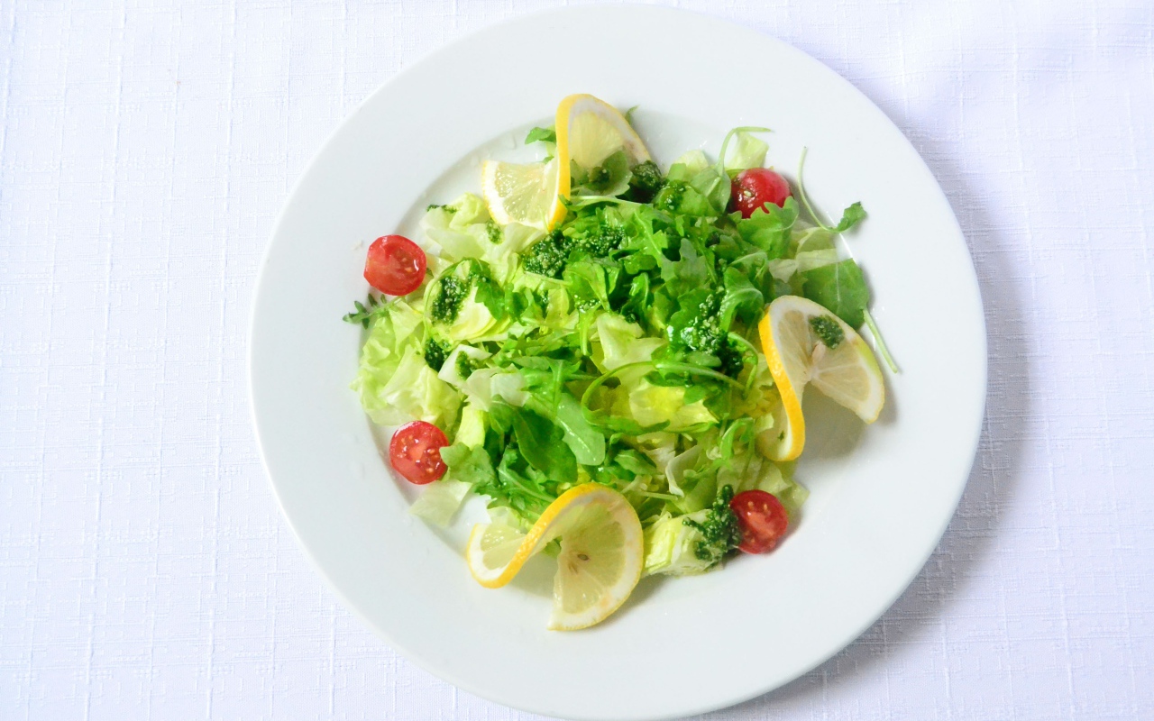 Салат из зелени с лимоном на белом фоне 