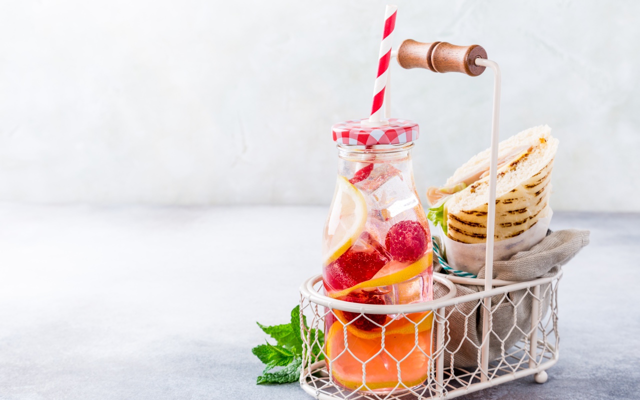 Банка с лимонадом в маленькой корзине с сэндвичем 