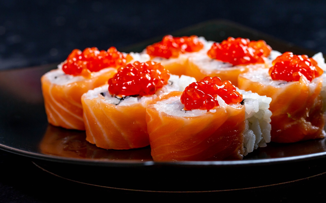 Роллы с красной икрой и рыбой на большой тарелке 