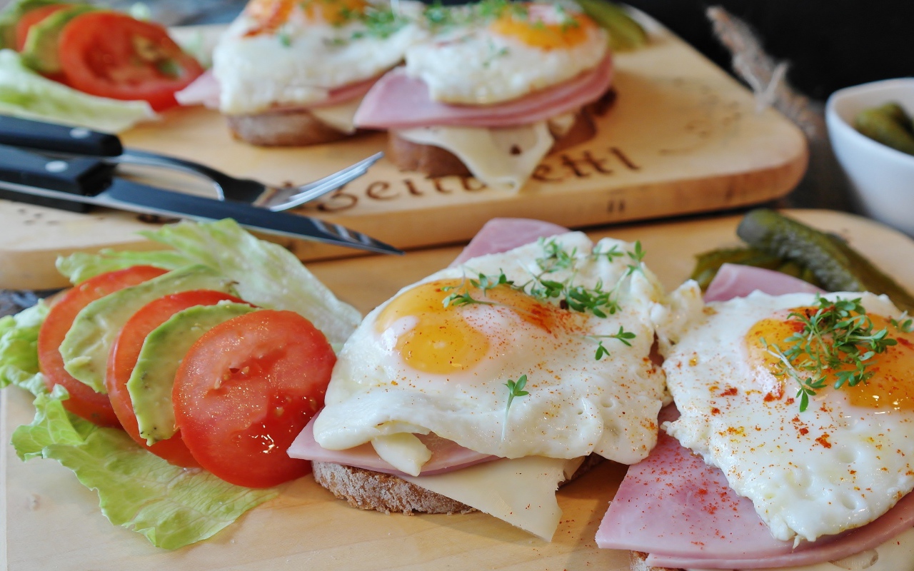 Бутерброды с яичницей и беконом на столе с овощами