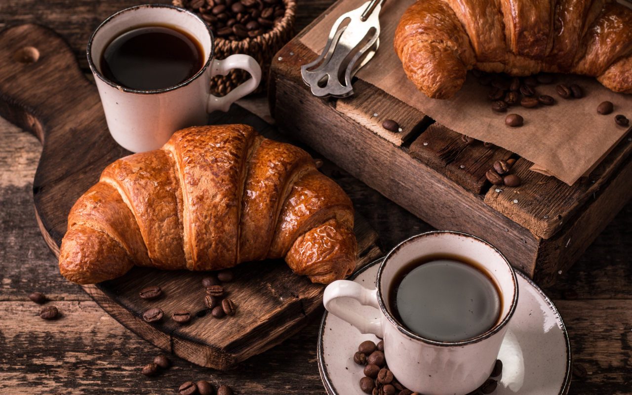 Две чашки кофе на столе с рогаликами и зернами 