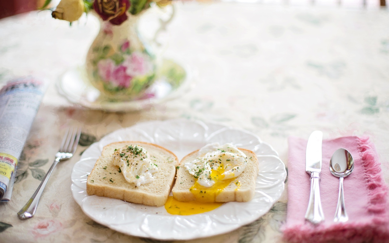 Два куска хлеба с яичницей на белой тарелке на завтрак 