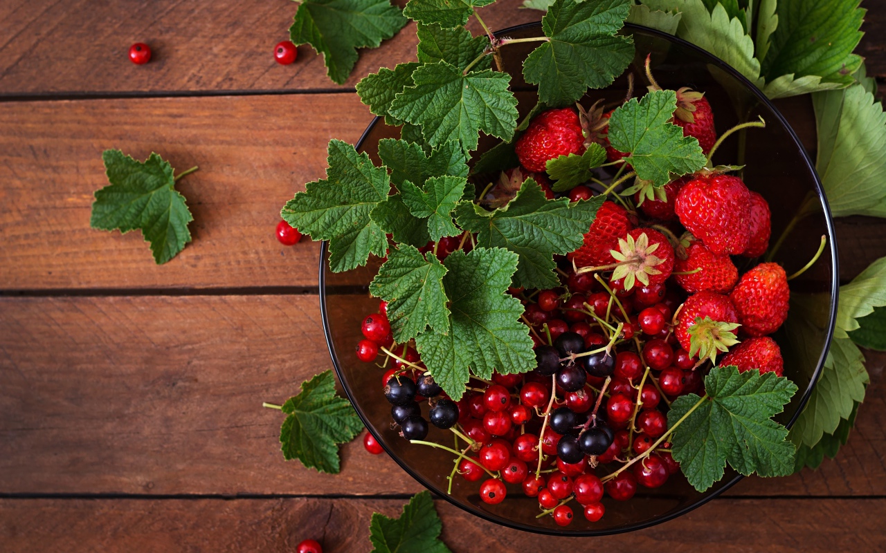 Ягоды смотродины в миске с клубникой и зелеными листьями