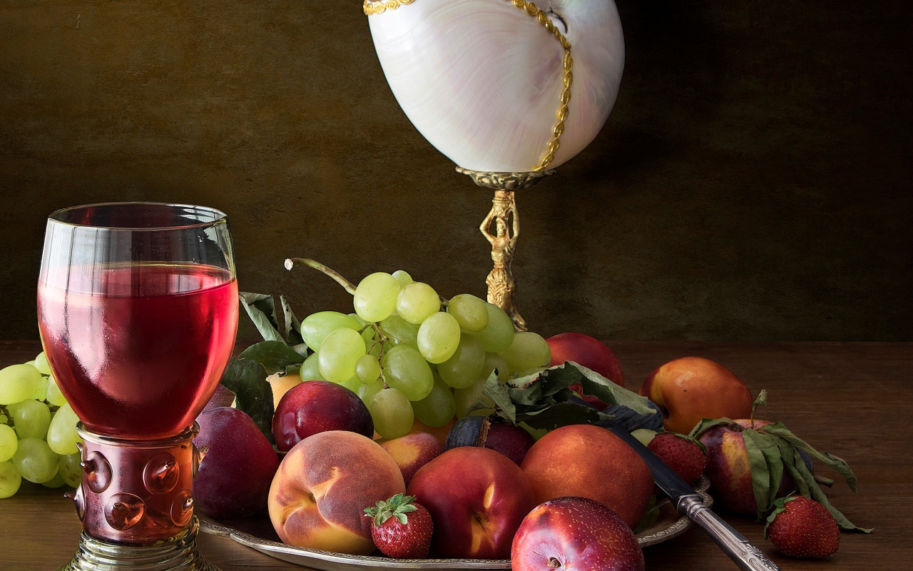 Свежие фрукты и ягоды на столе с вином и лампой 