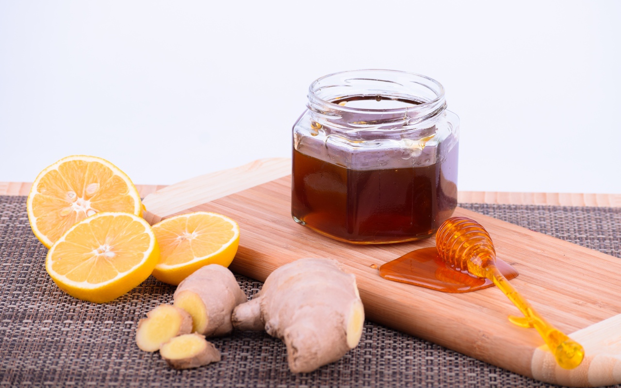 Jar of honey on a board with lemon and ginger root