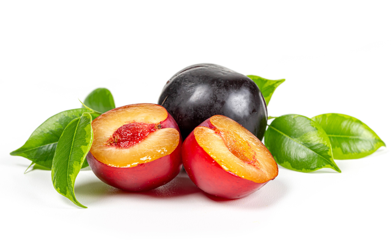 Сочные аппетитные сливы на белом фоне с зелеными листьями