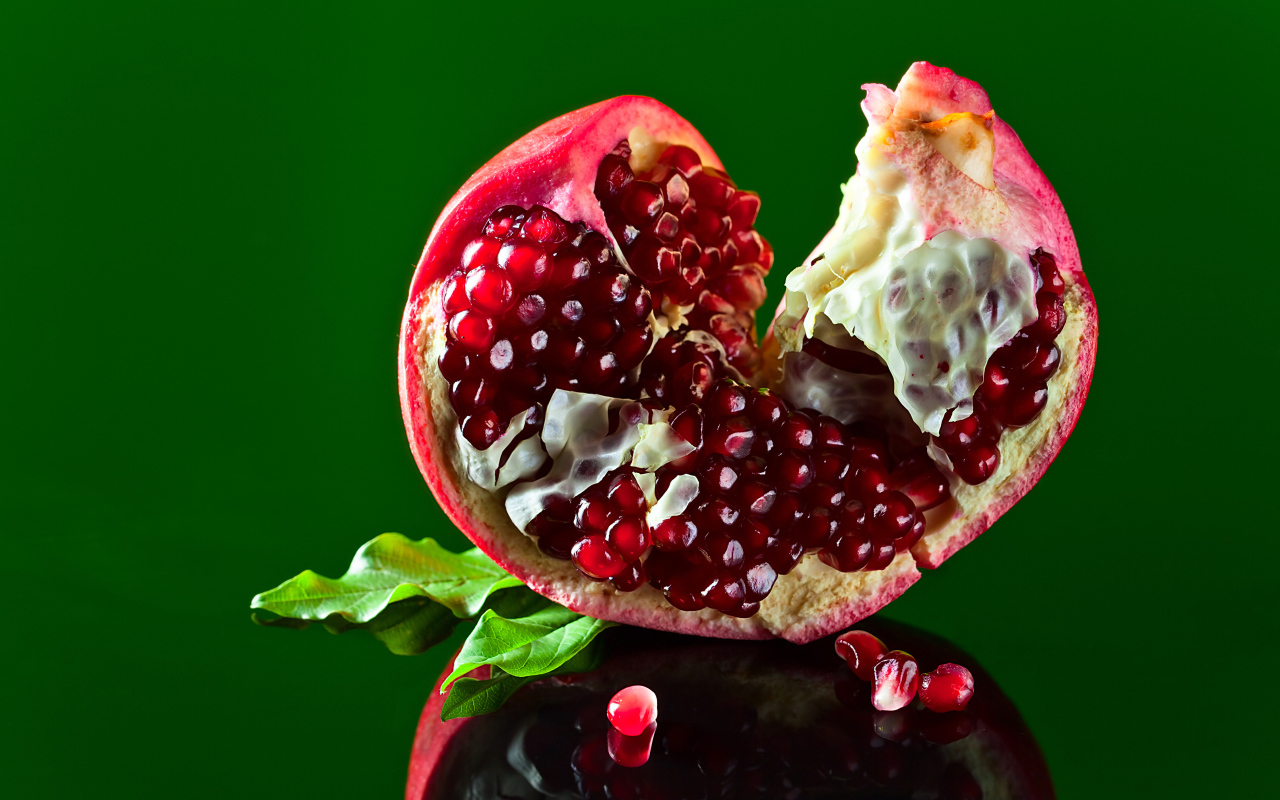 Очищенный гранат на зеленом фоне