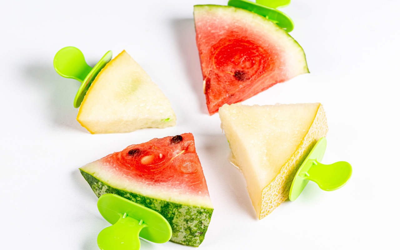 Pieces of watermelon and melon on sticks on white background