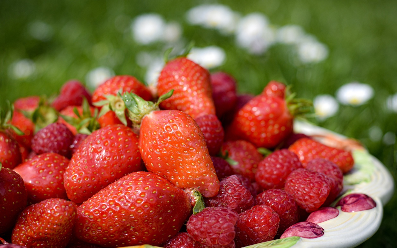 Спелая малина с ягодами клубники в тарелке 