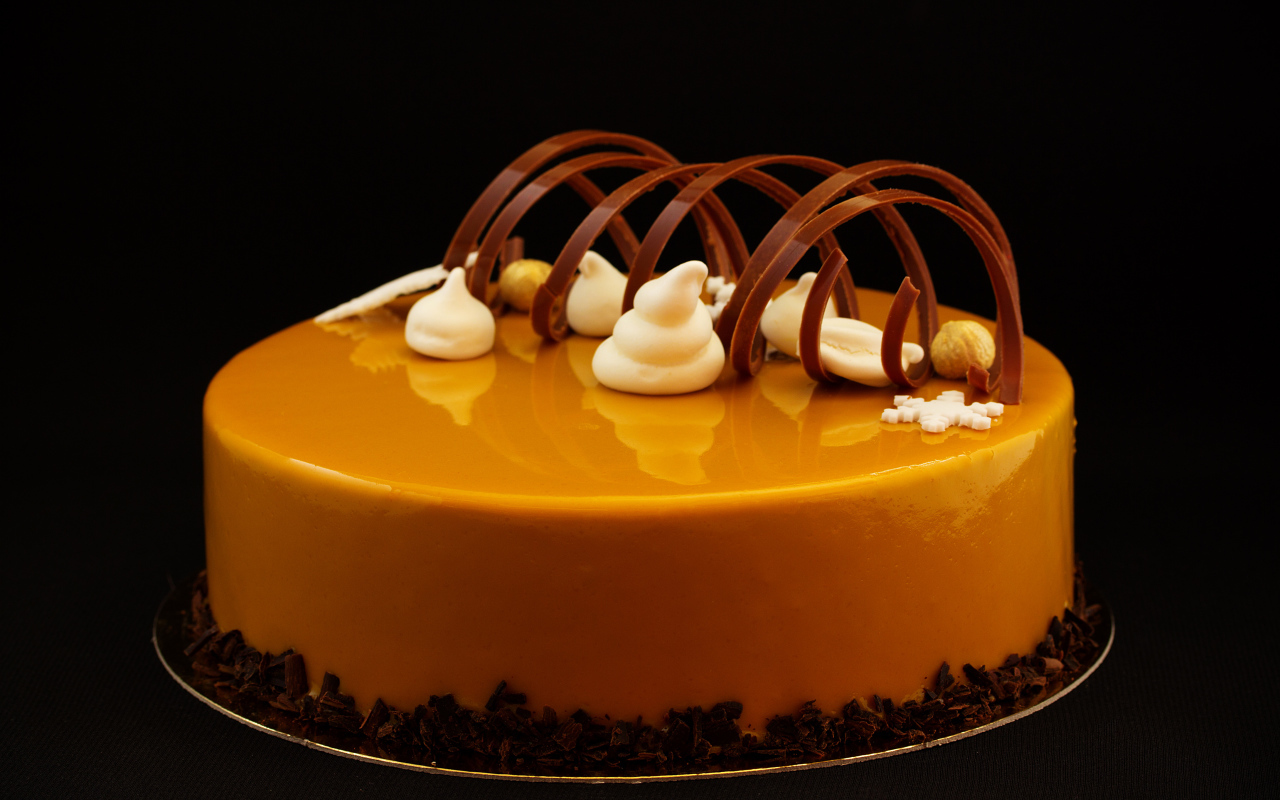 Красивый глянцевый оранжевый торт на черном фоне