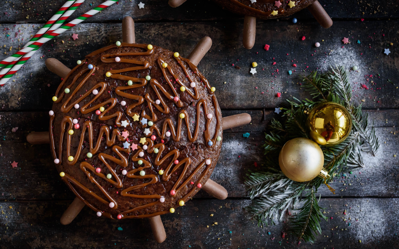 Шоколадное пирожное на столе с еловыми игрушками 