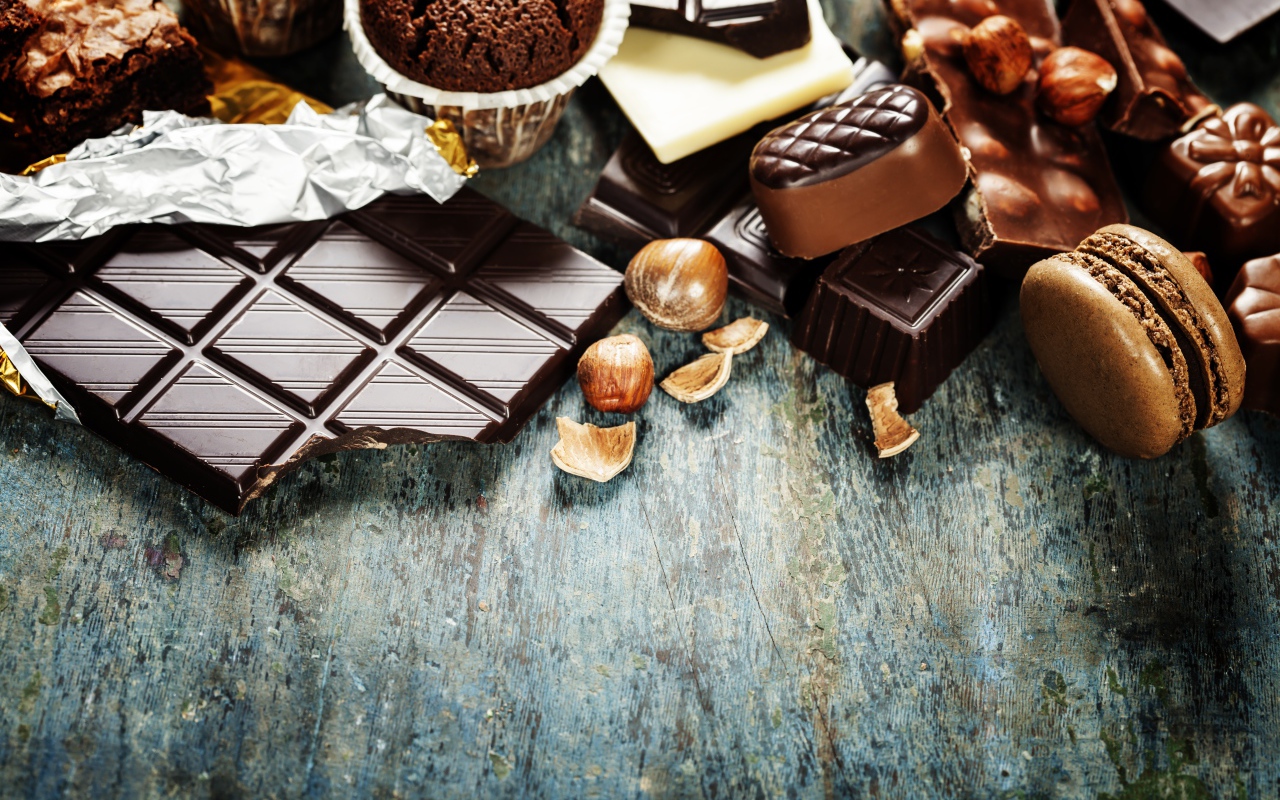 Шоколад на столе с орехами, кексами и конфетами 