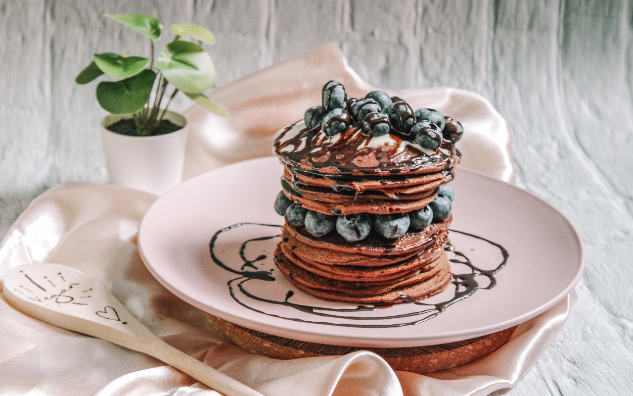 Шоколадные оладьи с ягодами черники на белой тарелке