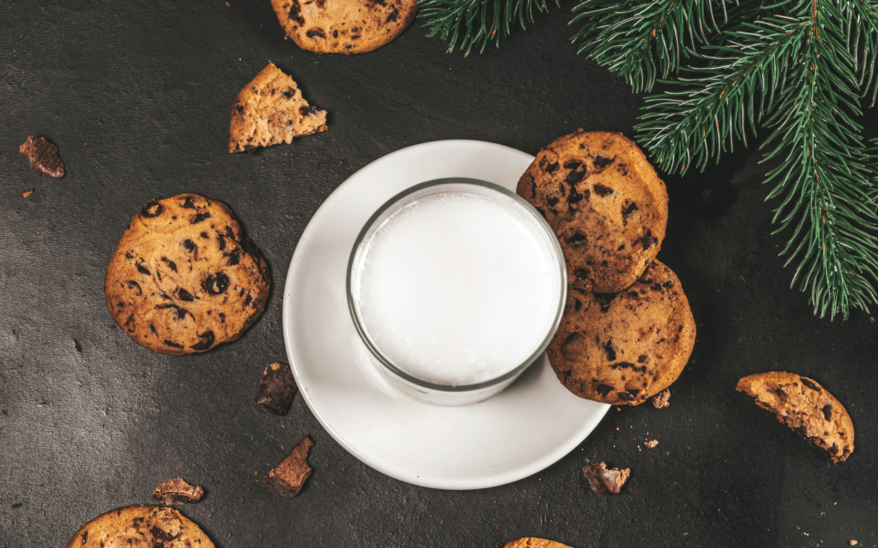 Печенье с шоколадом на столе со стаканом молока 