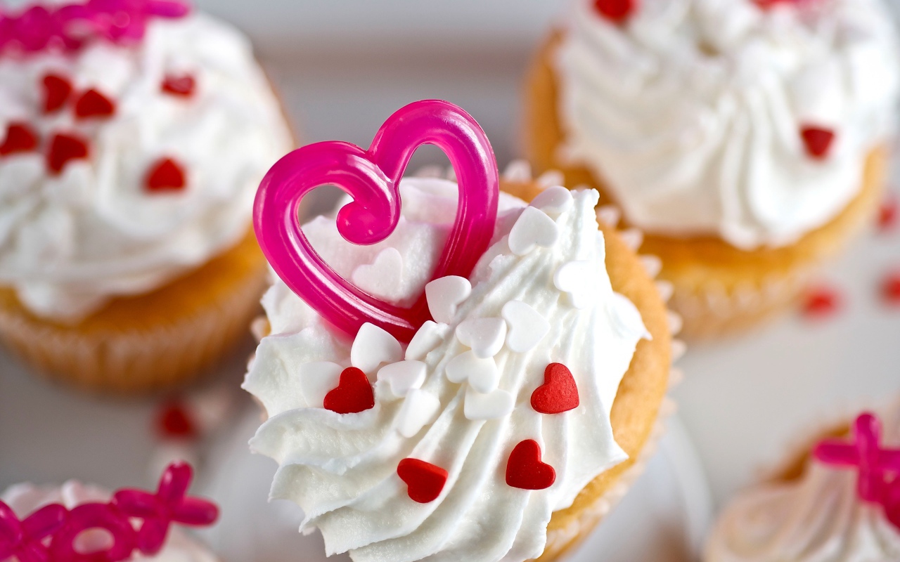 Кексы с кремом и сердечками на столе 