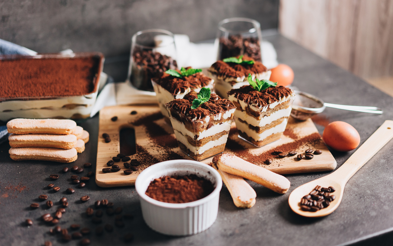 Аппетитный десерт тирамису в креманках на столе с кофейными зернами