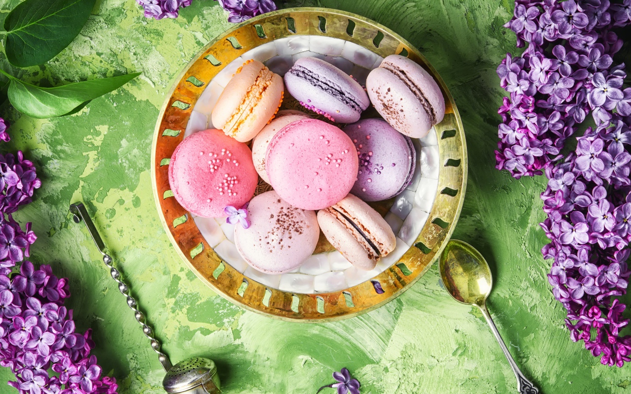 Разный десерт макарон на столе с цветами сирени 