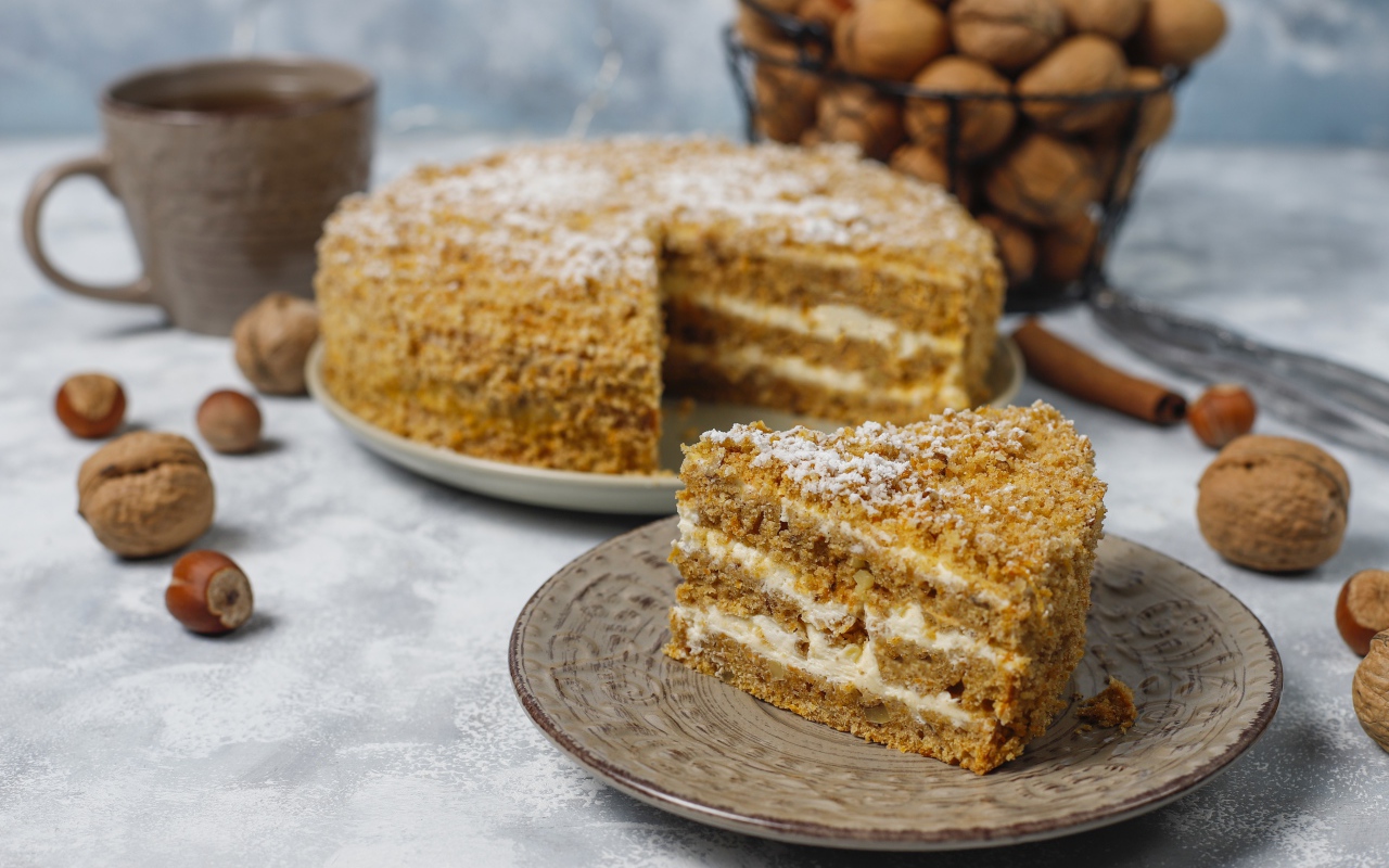 Торт медовик на столе с орехами и чашкой кофе