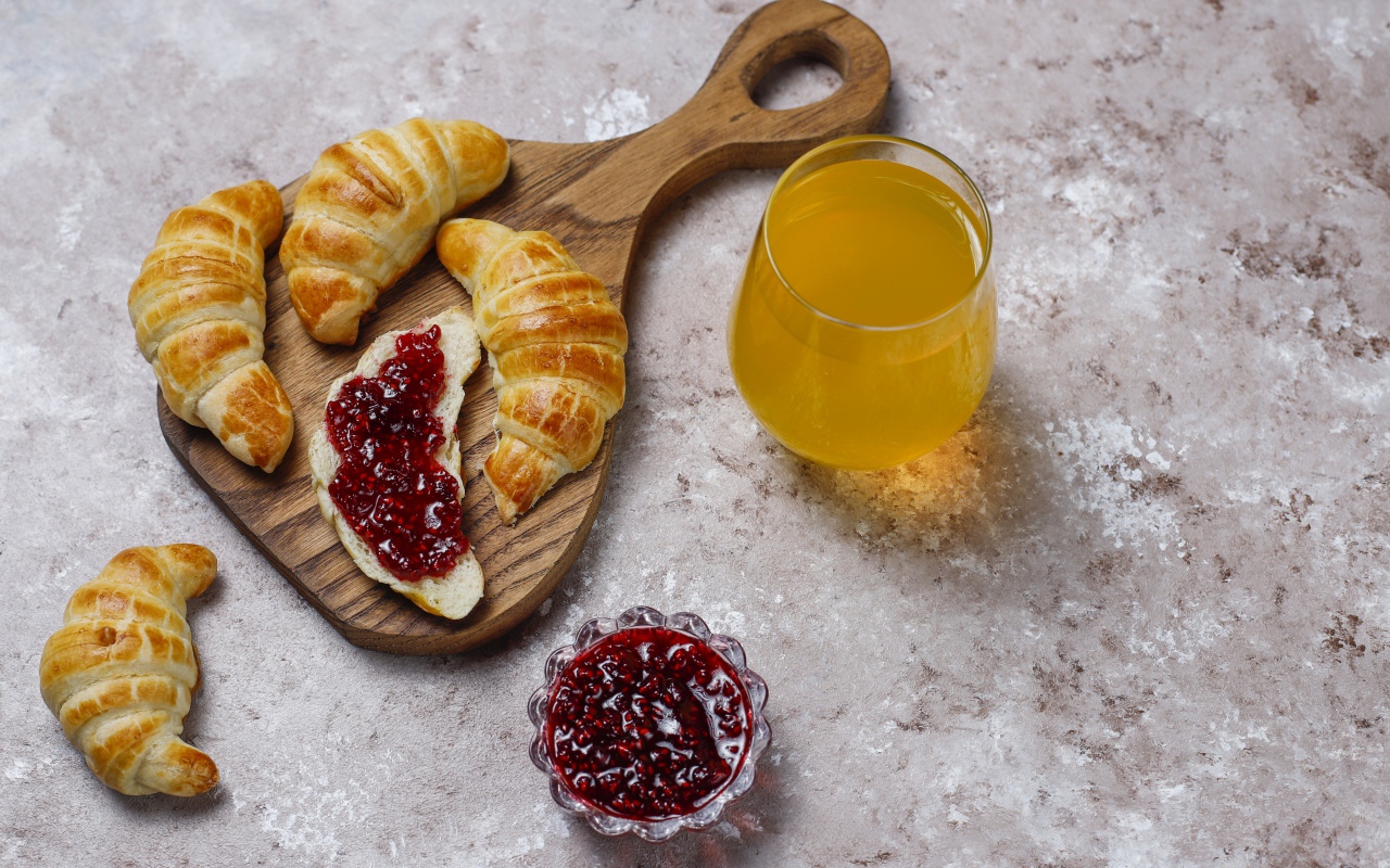 Сок на столе с круассанами и джемом
