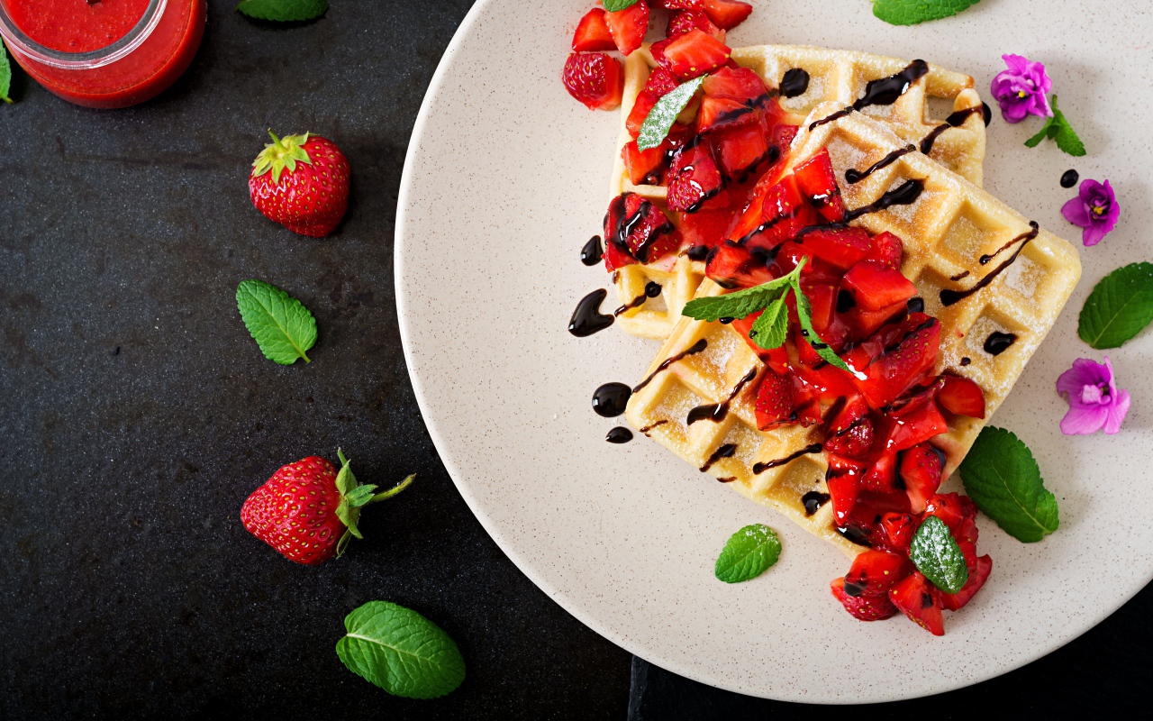 Large waffles with strawberries and chocolate on a white plate