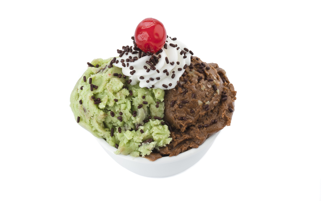 Фисташковое и шоколадное мороженое в креманке на белом фоне