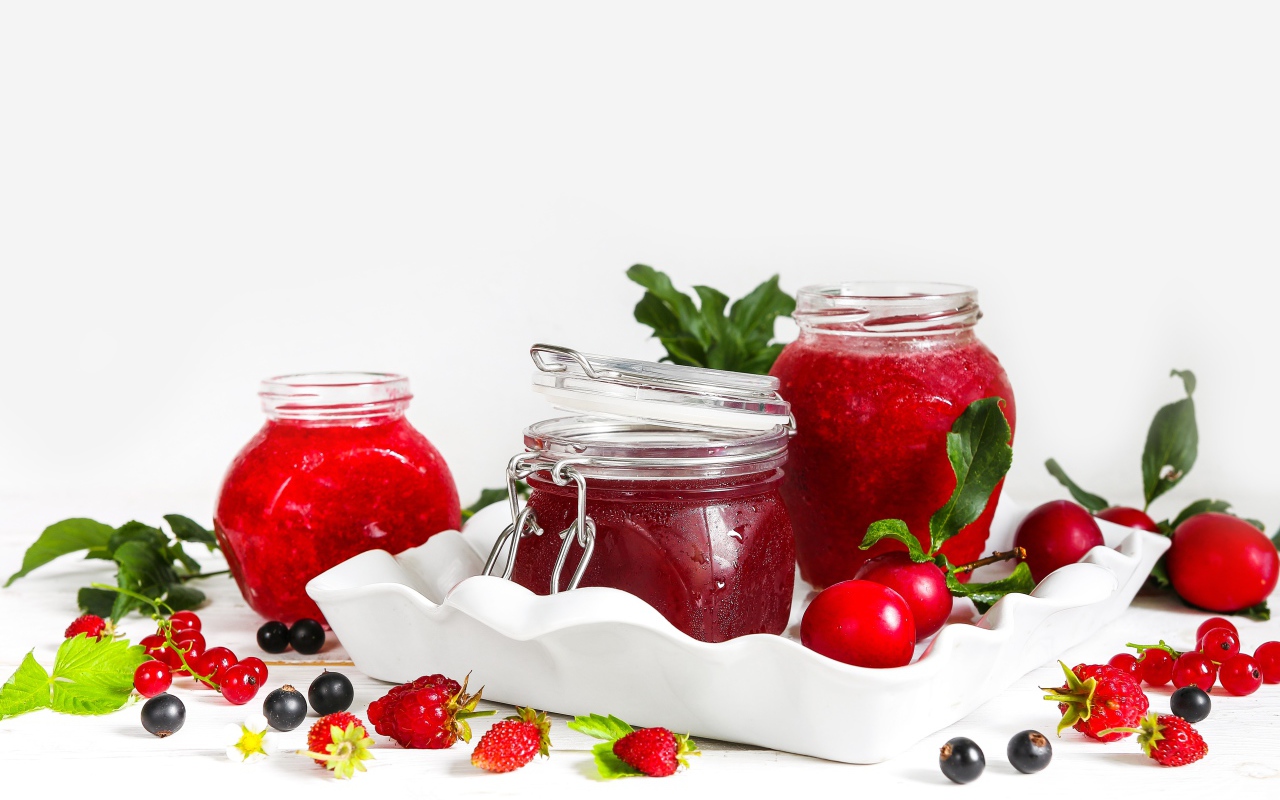Три банки джема с ягодами на белом фоне