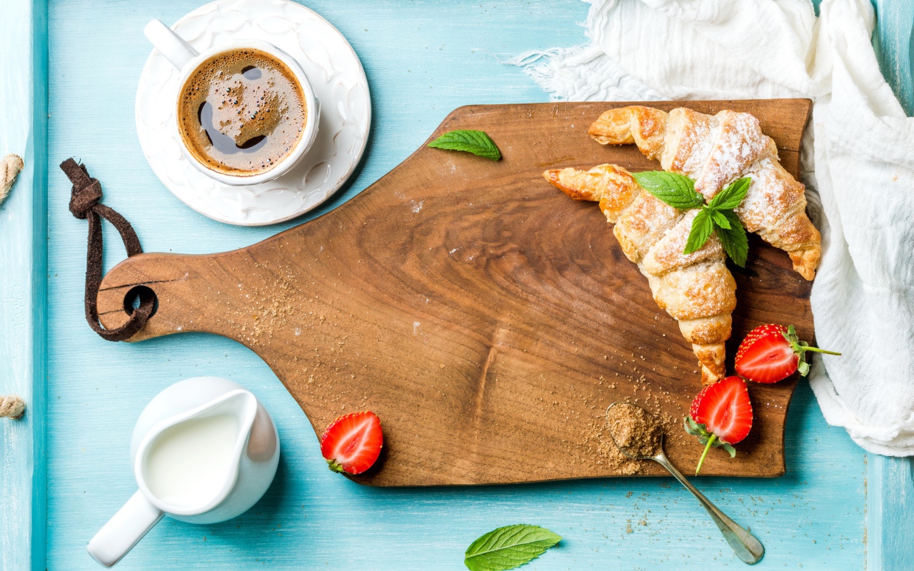 Wooden board on table with croissants and a cup of coffee
