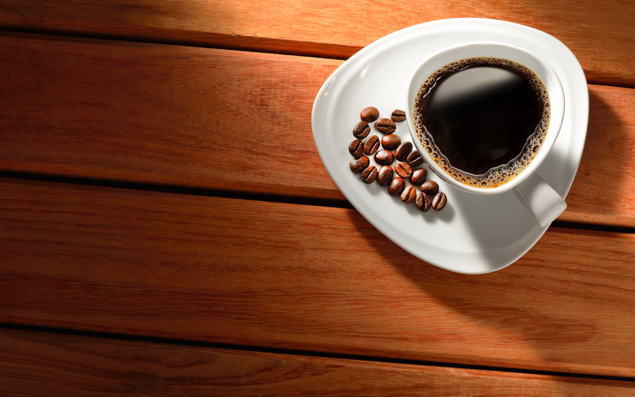 Чашка кофе на тарелке с зернами на деревянном столе
