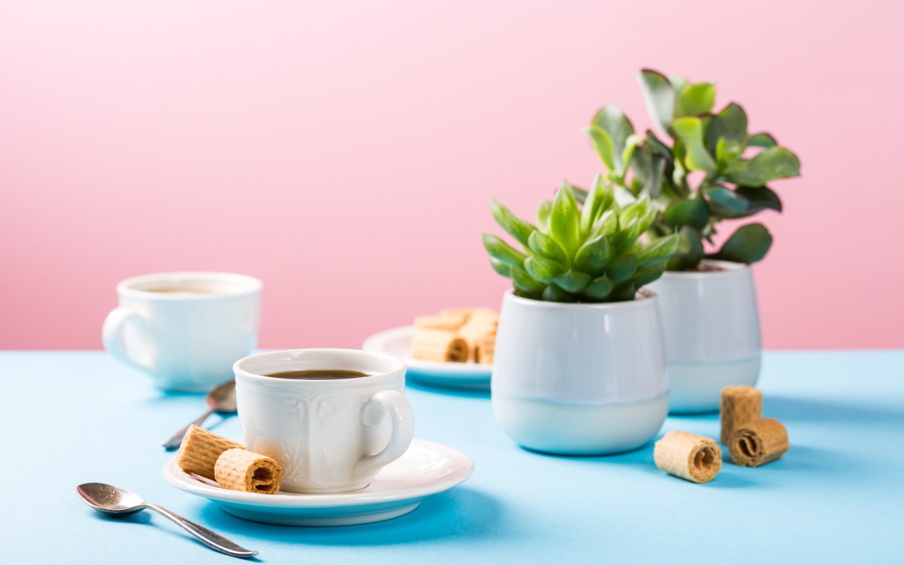 Чашка кофе на блюдце с вафлями на столе с цветами