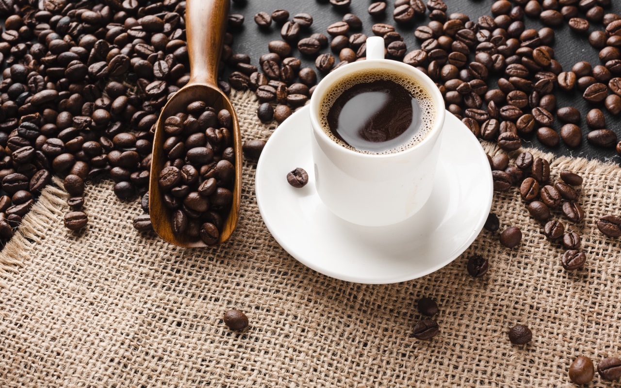 Чашка кофе на столе с зернами 