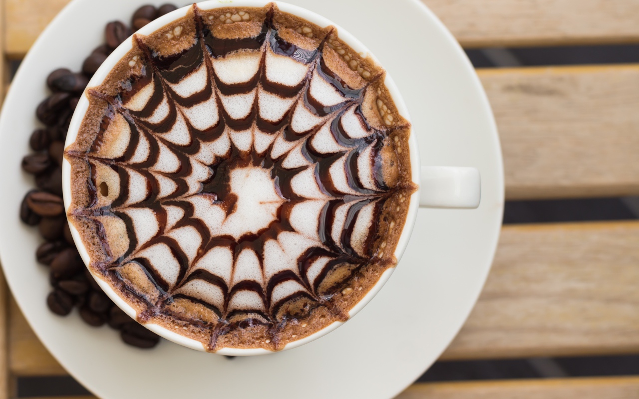 Чашка кофе с рисунком на пене на столе