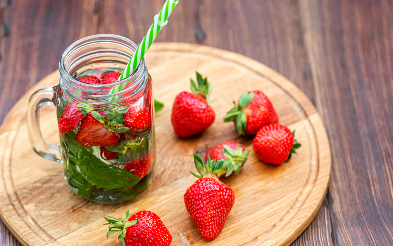 Напиток  в банке с ягодами клубники и трубочкой