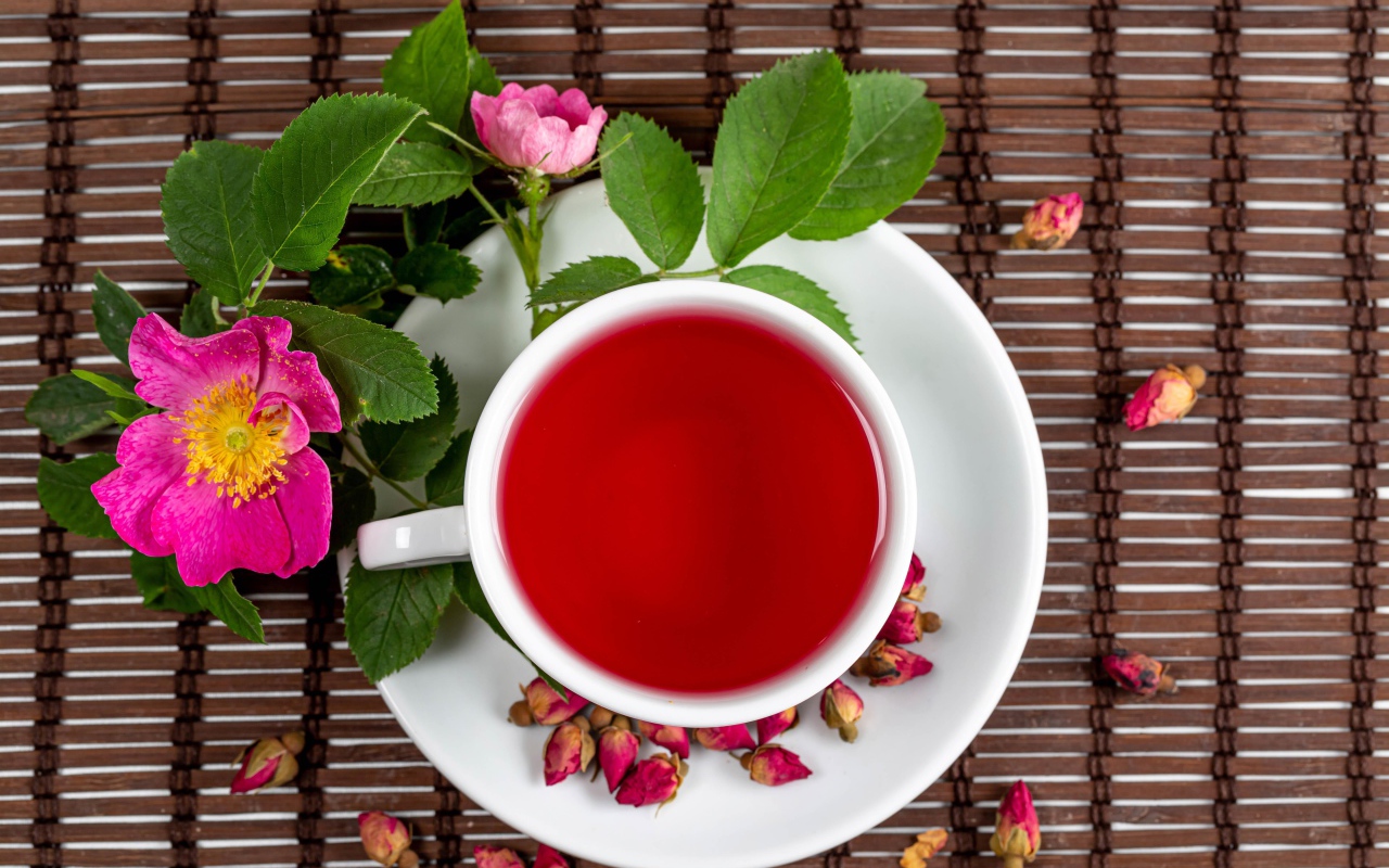Красный чай с шиповника на столе с цветами