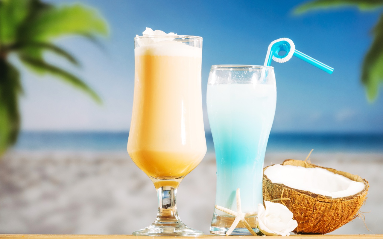 Два коктейля с кокосом на столе на тропическом пляже